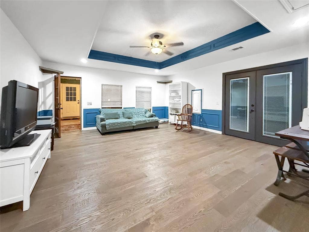 316 N Winding Oaks Drive, Wylie, TX 75098 Spacious room featuring wood-finish flooring, a tray ceiling with accent trim, and a ceiling fan