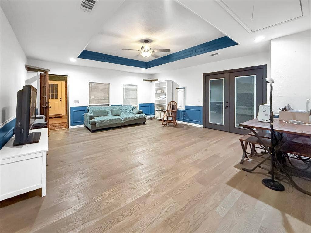 316 N Winding Oaks Drive, Wylie, TX 75098 Spacious living area featuring wood-finish flooring, a tray ceiling with a ceiling fan, and French doors