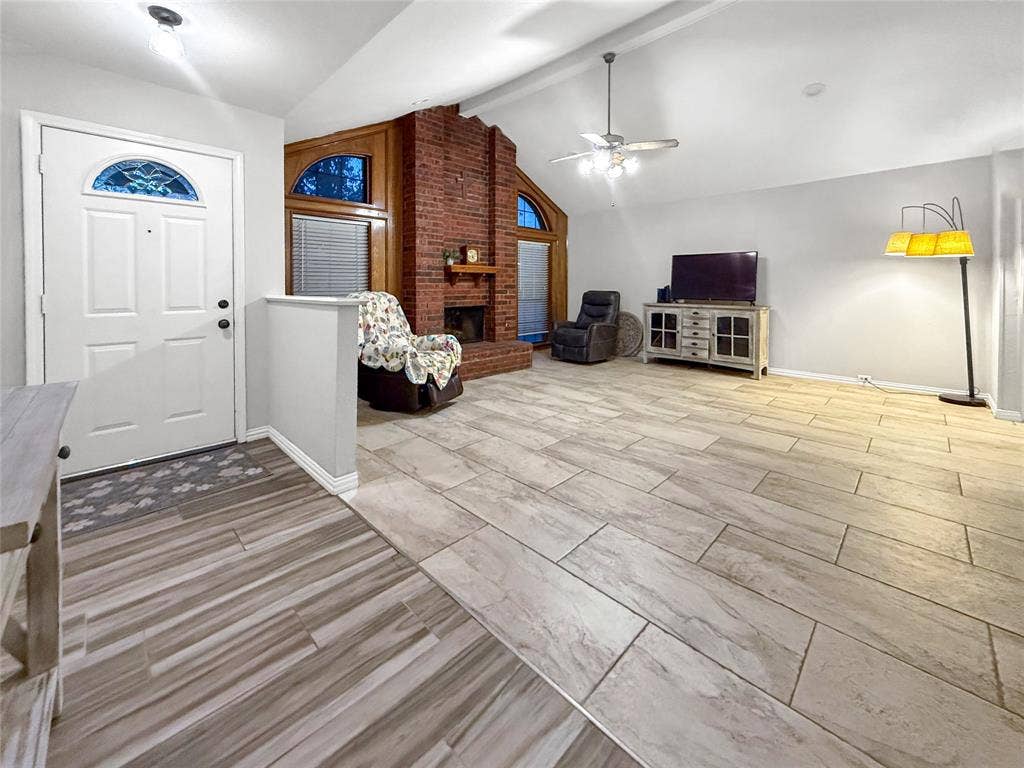 316 N Winding Oaks Drive, Wylie, TX 75098 Vaulted ceilings with a ceiling fan, brick fireplace with wood mantel, arched windows with wood trim, and tile flooring