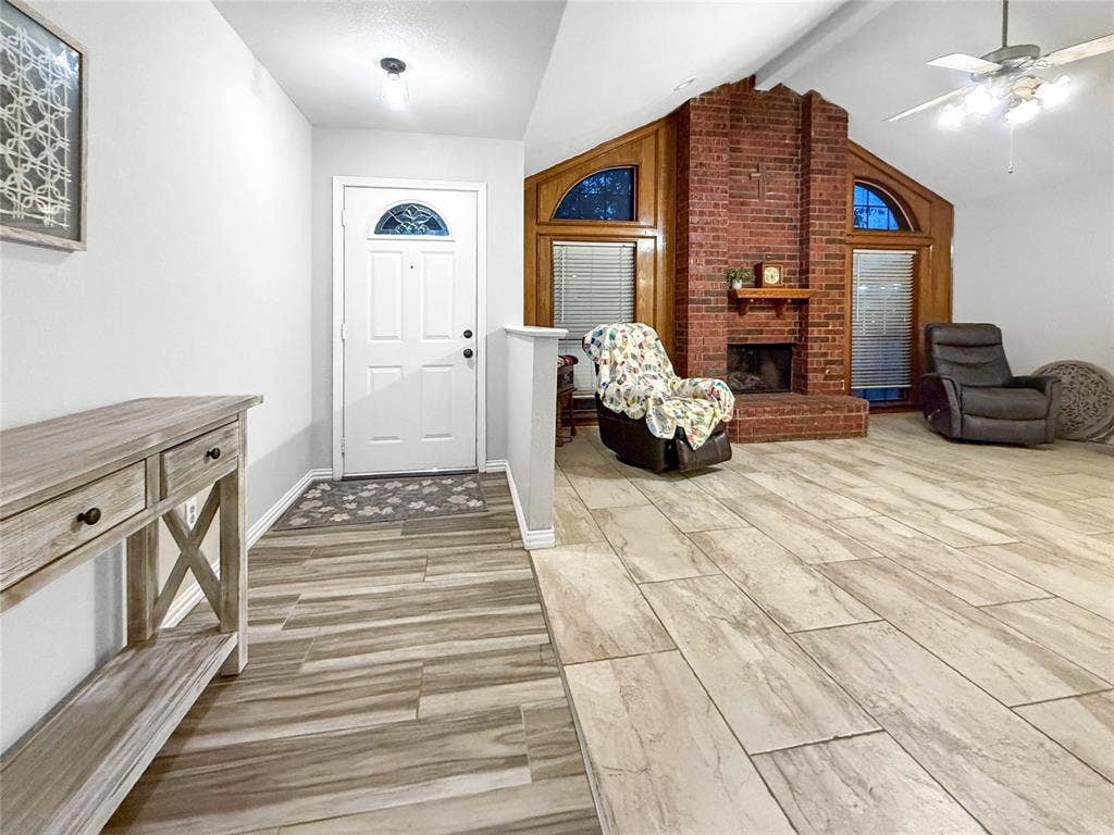 316 N Winding Oaks Drive, Wylie, TX 75098 Expansive living space featuring wood-finish flooring, a brick fireplace with a mantel, and vaulted ceilings
