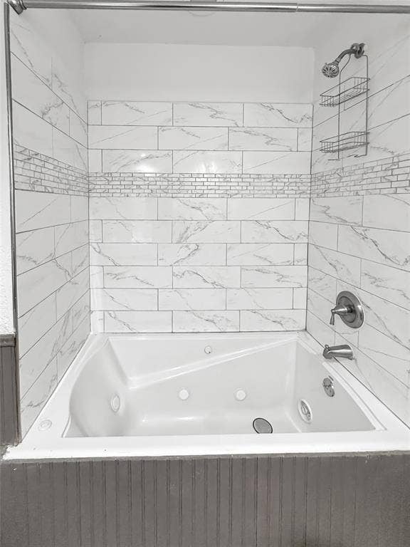 316 N Winding Oaks Drive, Wylie, TX 75098 Jetted soaking tub with a brushed nickel showerhead and faucet, surrounded by white subway tile with gray veining and a decorative mosaic accent band