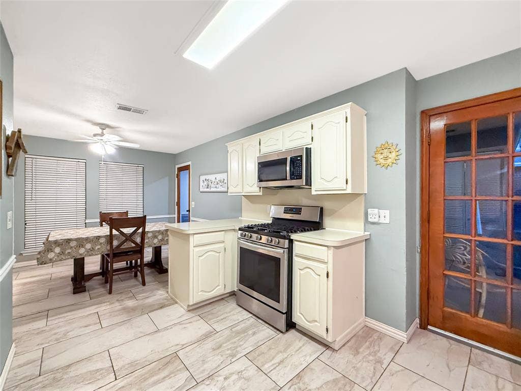 316 N Winding Oaks Drive, Wylie, TX 75098 Tile flooring, white cabinetry, stainless steel range, stainless steel microwave, and a wood-frame glass panel door