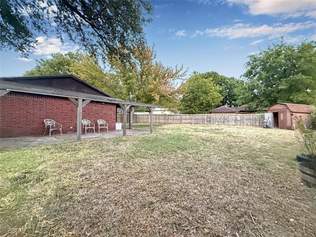316 N Winding Oaks Drive, Wylie, TX 75098 Expansive backyard featuring a brick exterior, covered patio, wood fencing, and a storage shed
