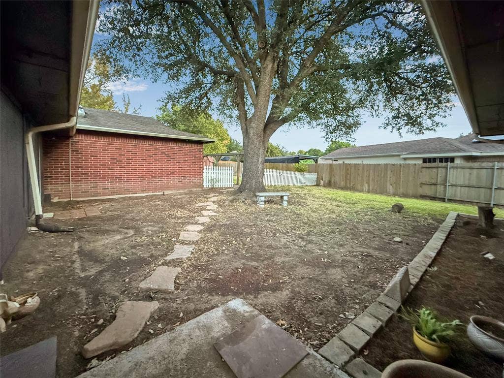 316 N Winding Oaks Drive, Wylie, TX 75098 Expansive backyard featuring a mature tree, stone pathway, and a privacy fence