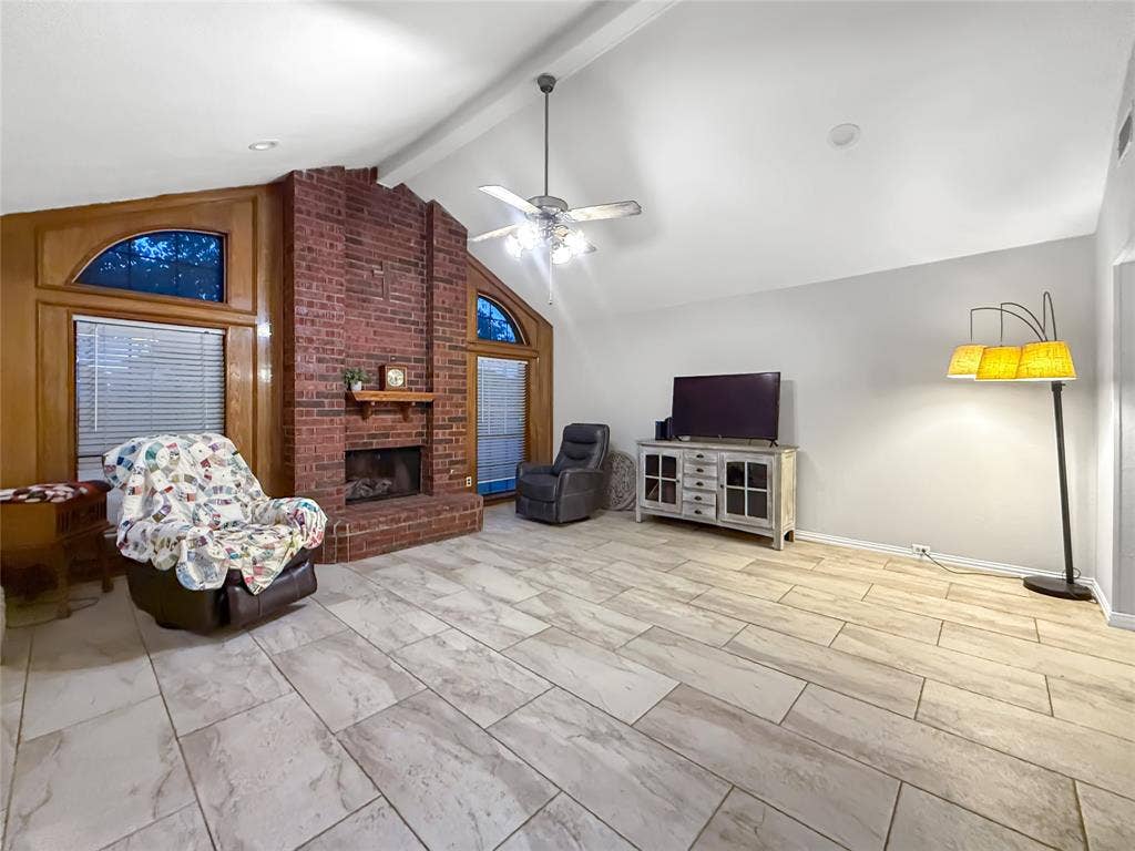 316 N Winding Oaks Drive, Wylie, TX 75098 Vaulted ceiling with a ceiling fan, brick fireplace with a wood mantle, wood-paneled accents, and tile flooring