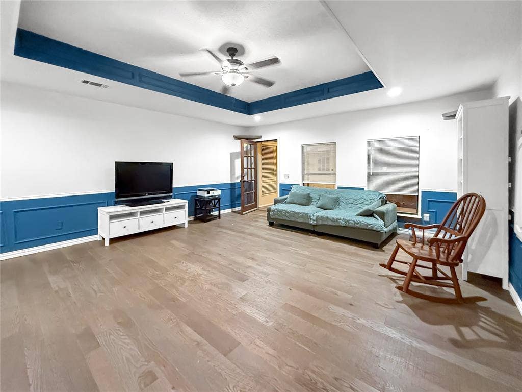 316 N Winding Oaks Drive, Wylie, TX 75098 Wood-finish flooring, accent wainscoting, tray ceiling with lighting, ceiling fan, and French doors
