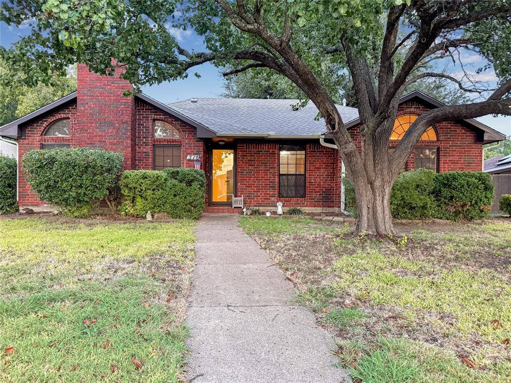 316 N Winding Oaks Drive, Wylie, TX 75098 Red brick exterior with a prominent chimney, arched windows, and a mature front yard tree