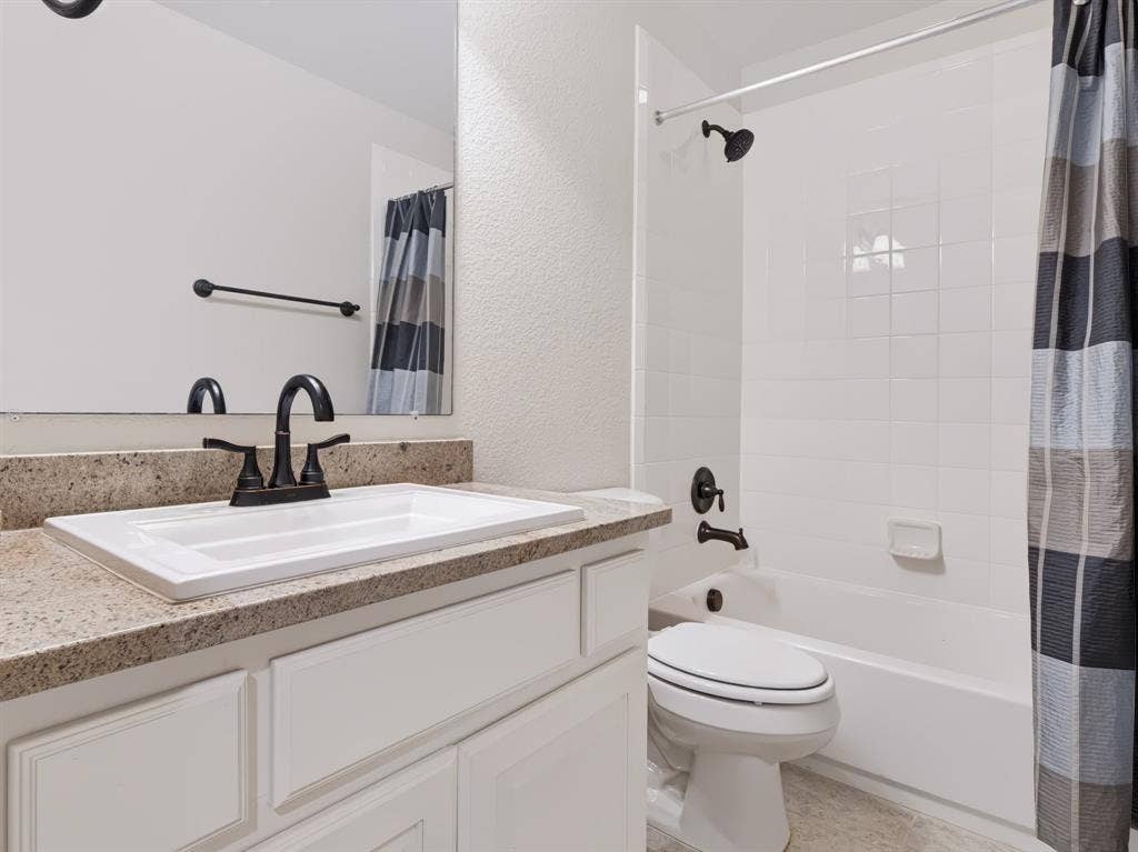 Bathroom featuring a white vanity with paneling, a rectangular sink, a speckled countertop, and oil-rubbed bronze fixtures