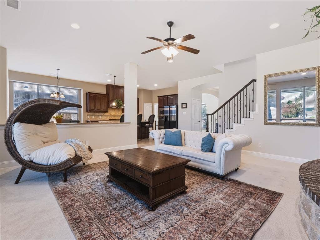 Open-concept living space featuring recessed lighting, a ceiling fan, and a staircase with wrought iron balusters