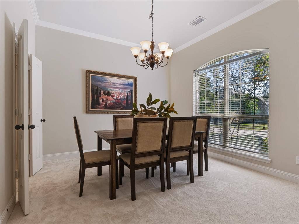 Arched window with blinds, carpeted flooring, crown molding, and a five-light chandelier