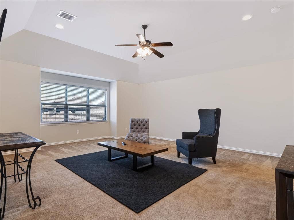 Spacious room featuring a vaulted ceiling with a ceiling fan, recessed lighting, and ample natural light from a large window