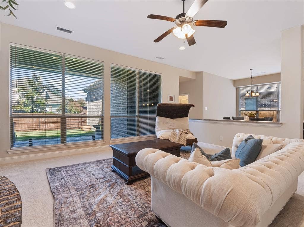 Recessed lighting, ceiling fan with wood-finish blades, and multiple windows with blinds