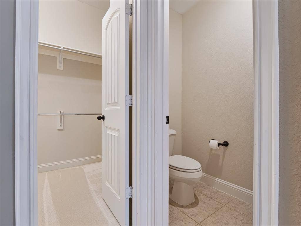Beadboard interior door with black hardware, white baseboards, and wall-mounted shelving