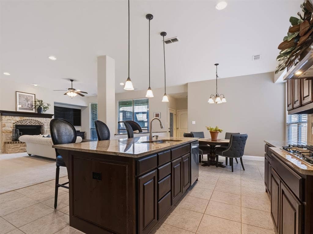 Kitchen featuring dark wood-finish cabinetry, light-toned tile flooring, and pendant lighting