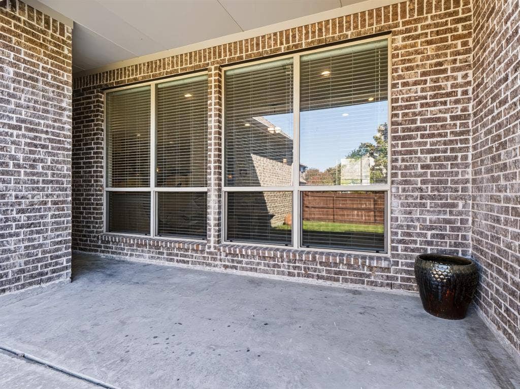 Covered concrete patio with brick exterior and large windows
