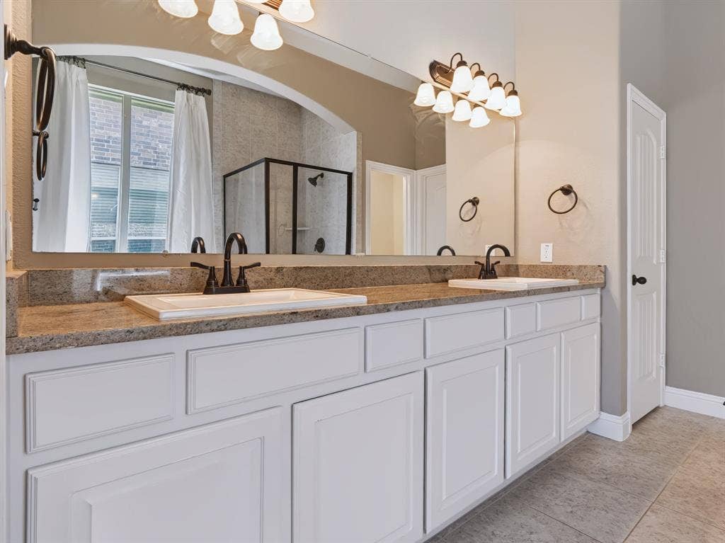 Double vanity with undermount sinks, granite countertop, and white cabinetry