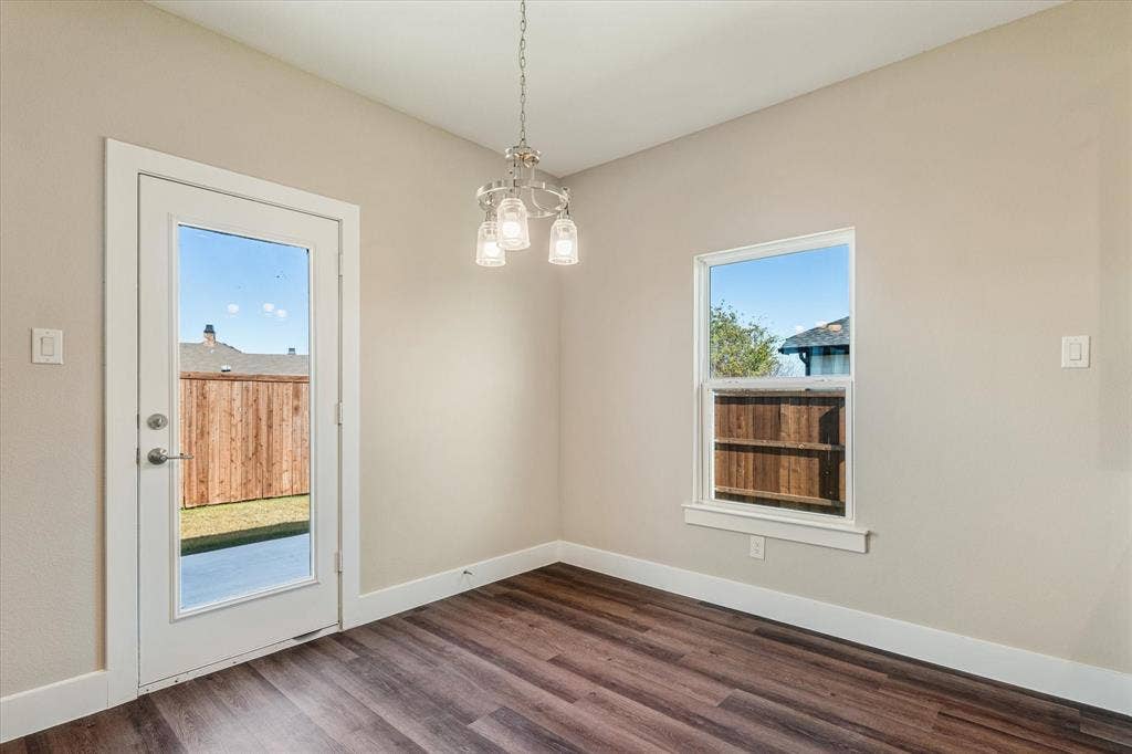 Wood-finish flooring, white baseboards, and a glass-paneled door