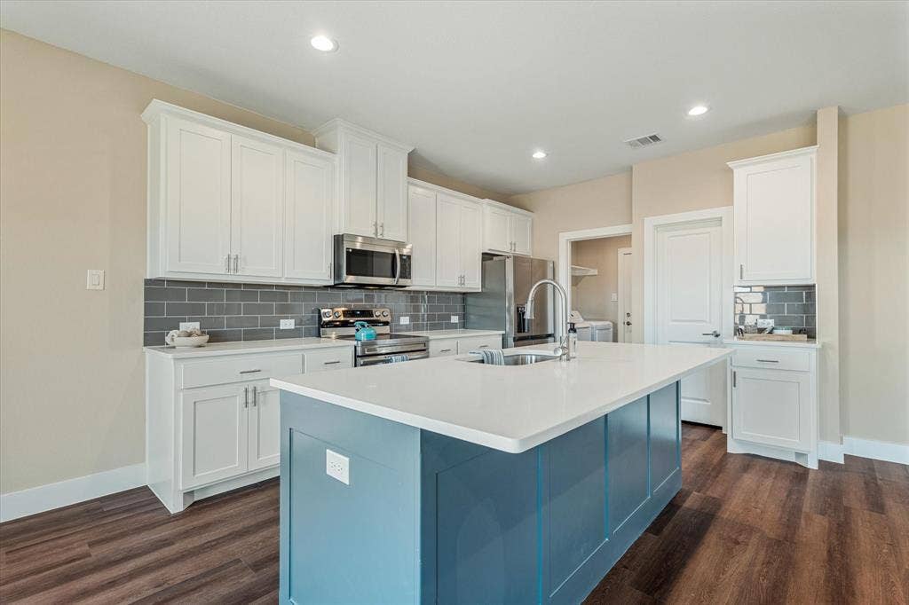 Kitchen with a central island, white shaker cabinetry, stainless steel appliances, a gray subway tile backsplash, and wood-finish flooring