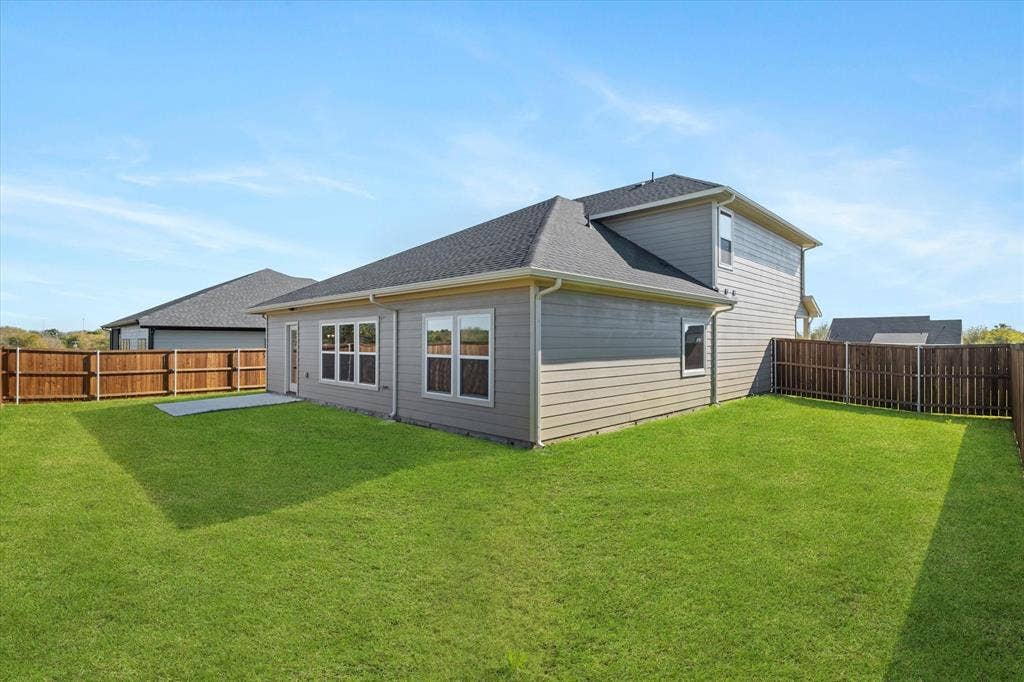 Expansive backyard featuring a manicured lawn, wood privacy fencing, and a concrete patio