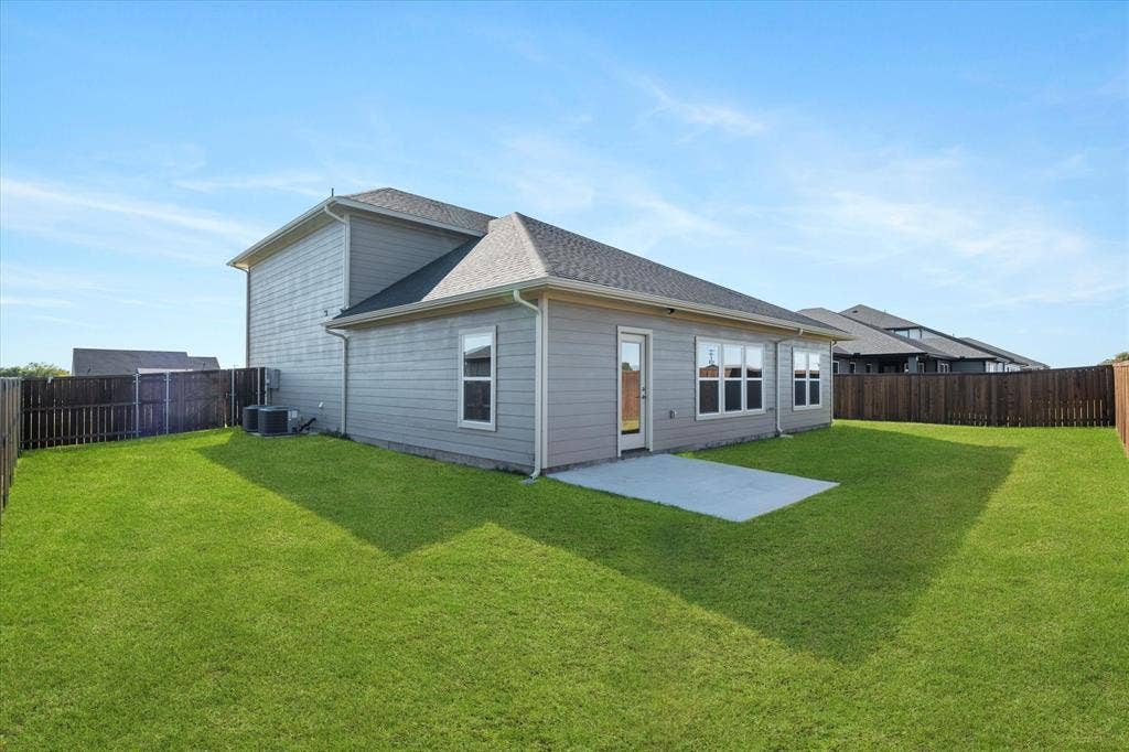 Expansive backyard featuring a manicured lawn, a privacy fence, a concrete patio, and a two-story exterior with siding