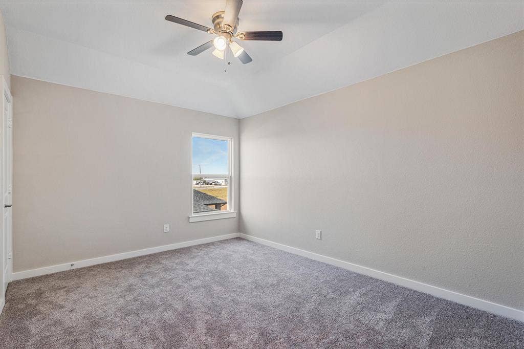 Vaulted ceiling with a flush-mount ceiling fan, neutral wall tones, and plush carpeting