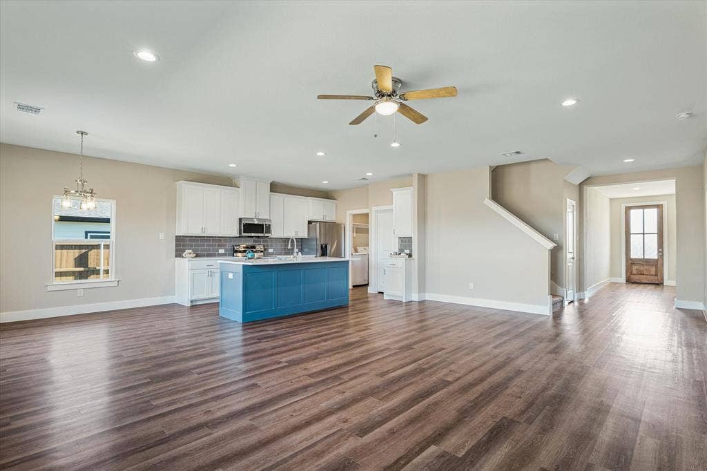 Open-concept living area with wood-finish flooring, recessed lighting, and a ceiling fan