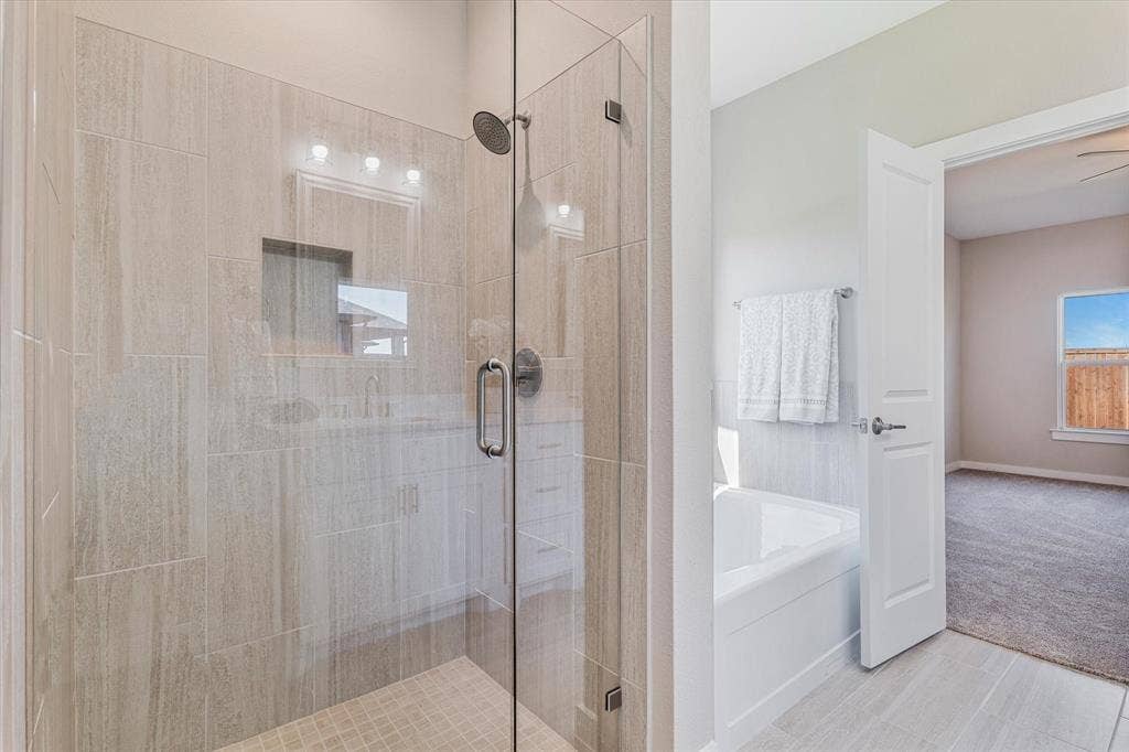 Glass-enclosed shower with tiled walls and floor, built-in shower niche, and an adjacent built-in bathtub