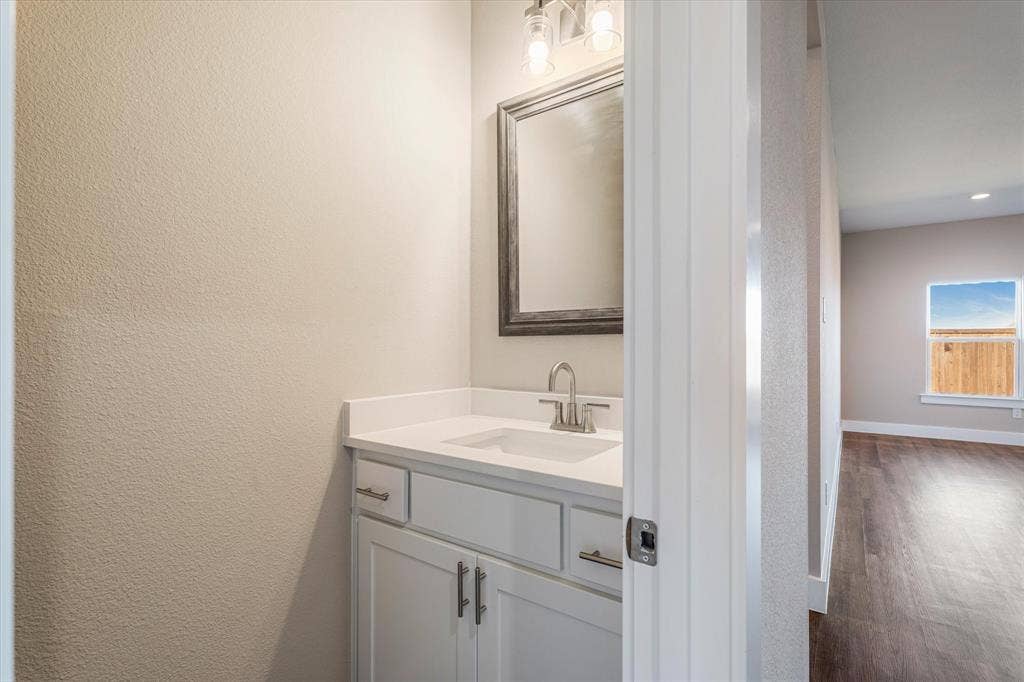 Vanity with white cabinetry, integrated sink, and stainless steel faucet