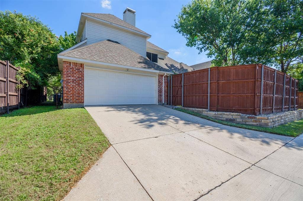 5925 Westmont Drive, Plano, TX 75093 Brick and siding exterior with a two-car garage, concrete driveway, and wood privacy fencing