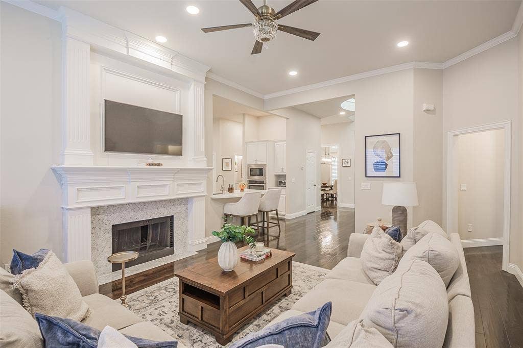 5925 Westmont Drive, Plano, TX 75093 Fireplace with a decorative mantel, wood-finish flooring, recessed lighting, crown molding, and a ceiling fan with light fixture