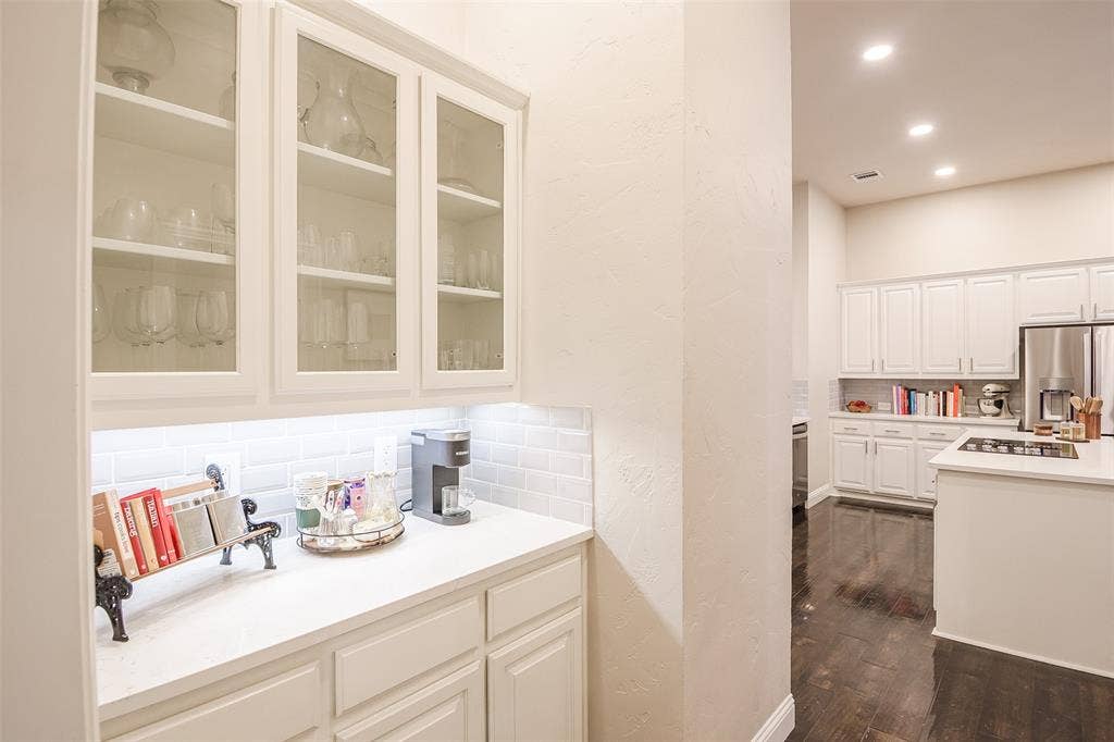 5925 Westmont Drive, Plano, TX 75093 Built-in cabinetry with glass-front uppers, solid surface countertops, subway tile backsplash, and recessed lighting