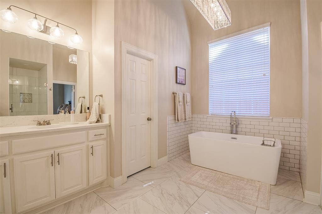 5925 Westmont Drive, Plano, TX 75093 Freestanding soaking tub, subway tile wainscoting, and a single vanity with a quartz countertop