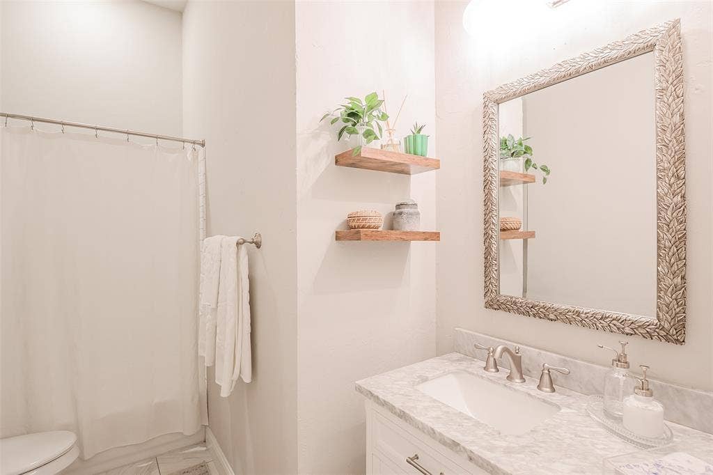 5925 Westmont Drive, Plano, TX 75093 White vanity with a light-toned countertop, undermount sink, and brushed nickel faucet