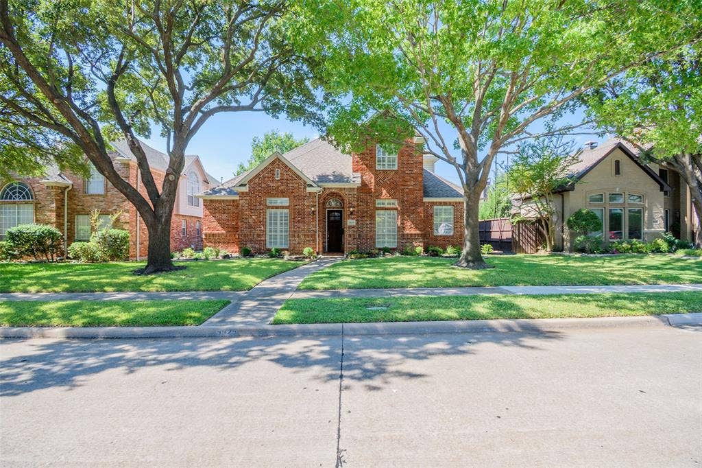 5925 Westmont Drive, Plano, TX 75093 Red brick exterior with white shutter accents, arched entryway, and a gabled roof