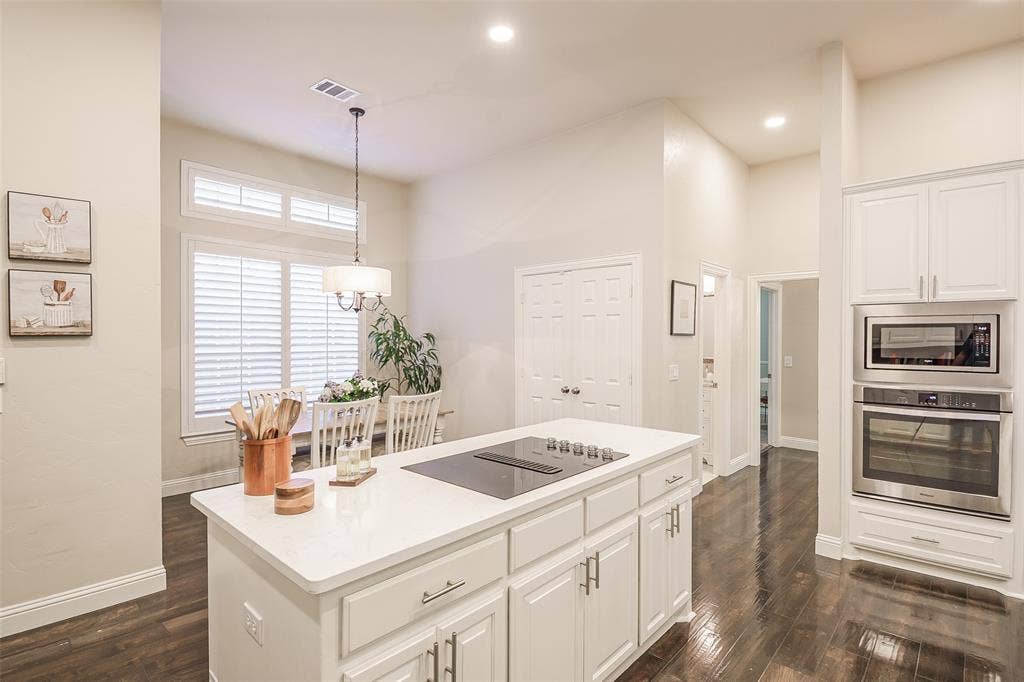 5925 Westmont Drive, Plano, TX 75093 Contemporary kitchen featuring a large center island with white cabinetry and quartz countertop, stainless steel sink, and pendant lighting