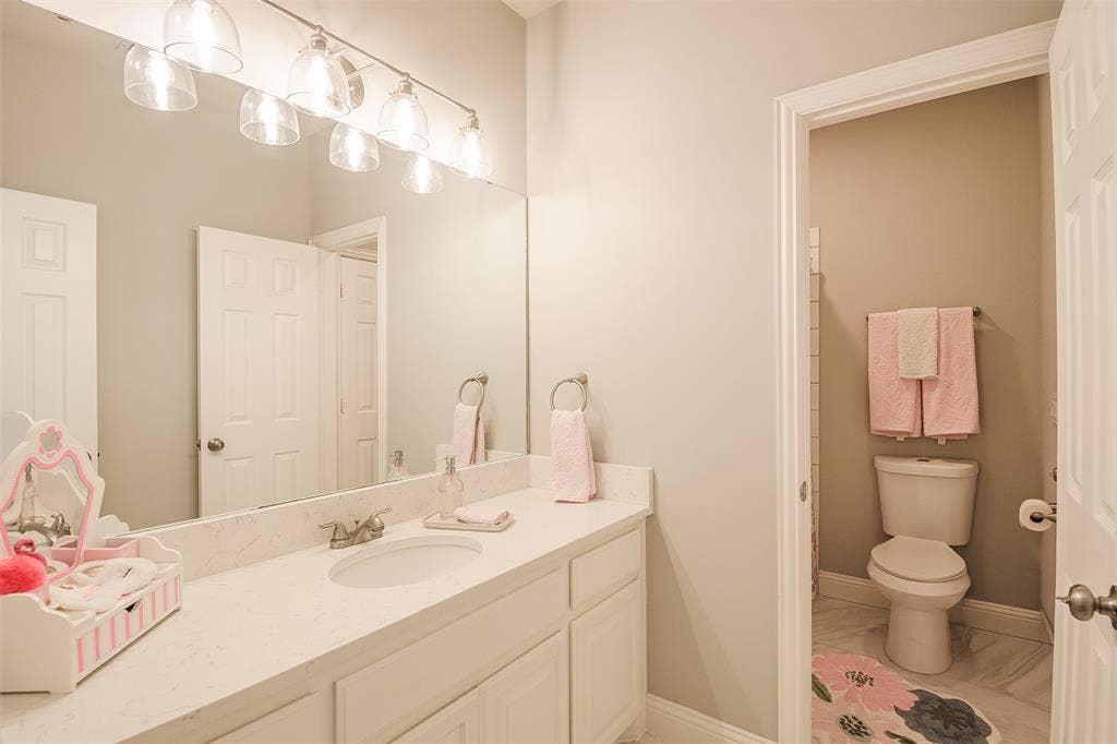 5925 Westmont Drive, Plano, TX 75093 Spa-inspired bathroom featuring a generous dual-sink vanity with ample countertop storage, polished chrome fixtures, and a large framed mirror with integrated vanity lighting