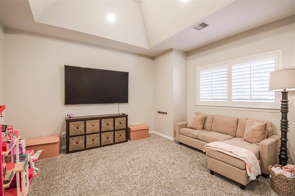 5925 Westmont Drive, Plano, TX 75093 Carpeted room with a vaulted ceiling, wall-mounted television, and window with plantation shutters