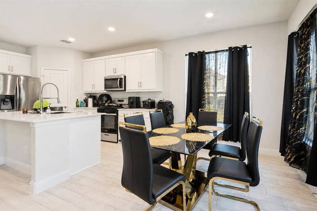 2902 Cremini Fls, Princeton, TX 75407 Kitchen featuring white cabinetry, stainless steel appliances, a center island with a sink, and wood-finish flooring