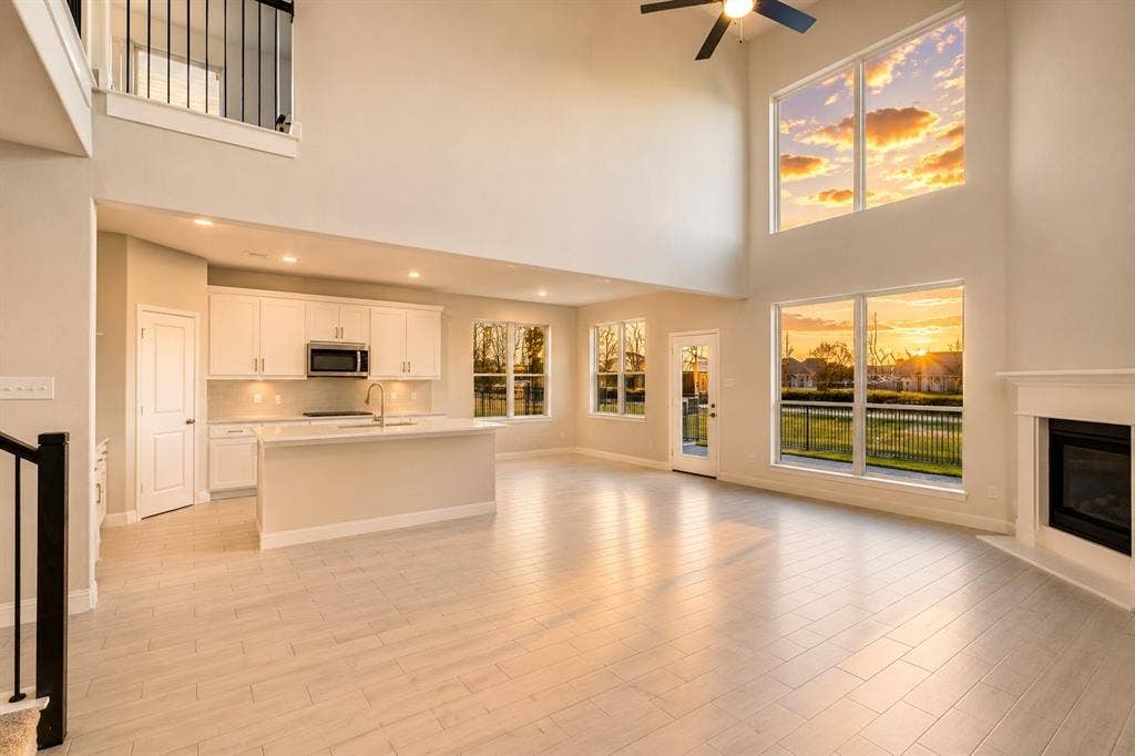2902 Cremini Fls, Princeton, TX 75407 Two-story living area with high ceilings, featuring a gas fireplace with a mantel, and large windows