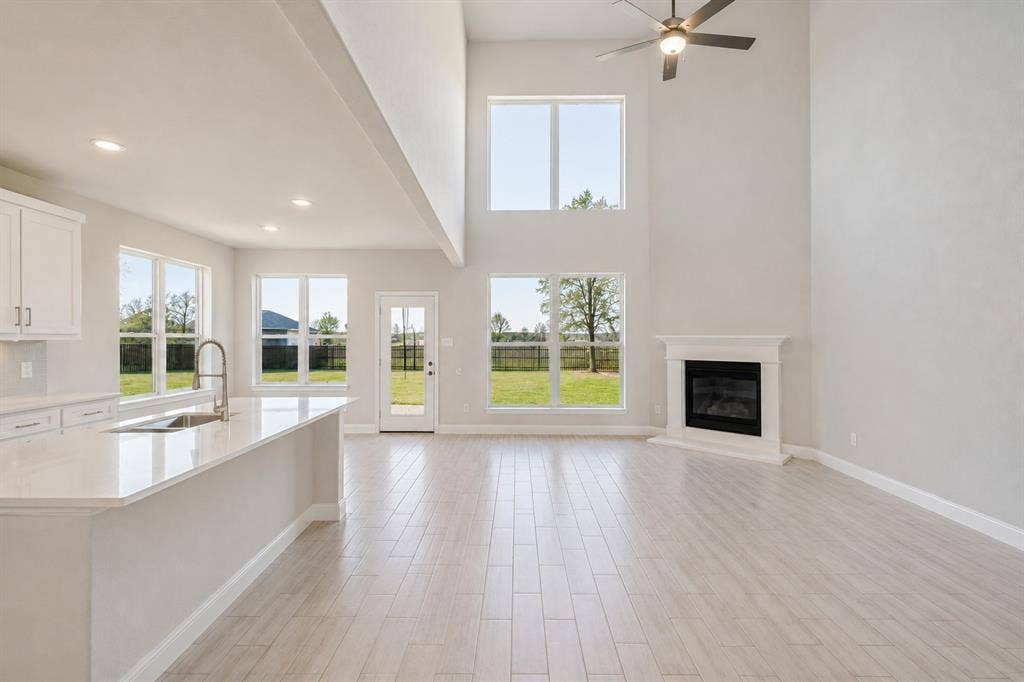 2902 Cremini Fls, Princeton, TX 75407 Vaulted ceilings with a ceiling fan, a fireplace with a mantel, light wood-finish flooring, and multiple windows