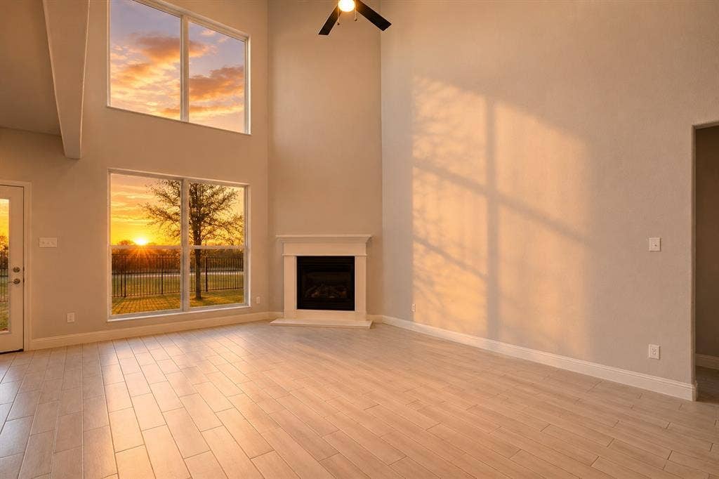 2902 Cremini Fls, Princeton, TX 75407 Two-story ceilings, wood-finish flooring, a fireplace with a white mantel, and large windows with transom panels