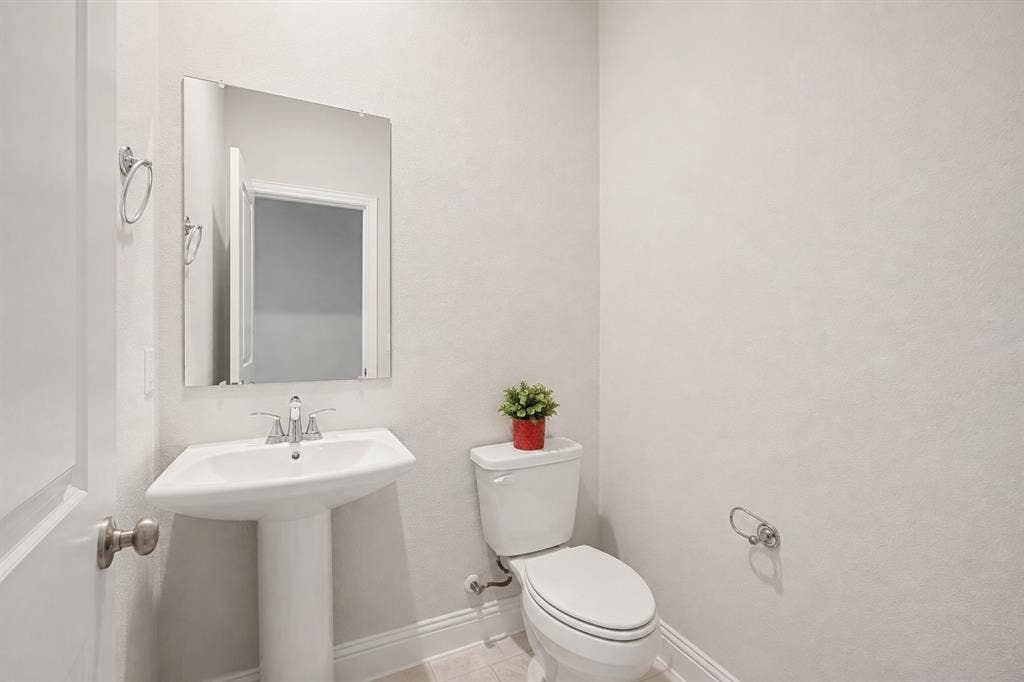 2902 Cremini Fls, Princeton, TX 75407 Pedestal sink with chrome faucet, wall-mounted mirror, and white toilet