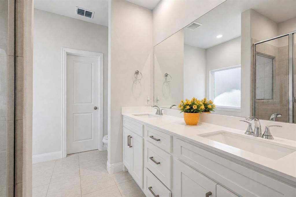 2902 Cremini Fls, Princeton, TX 75407 Dual vanity with integrated sinks, white cabinetry, chrome fixtures, and a large wall-mounted mirror