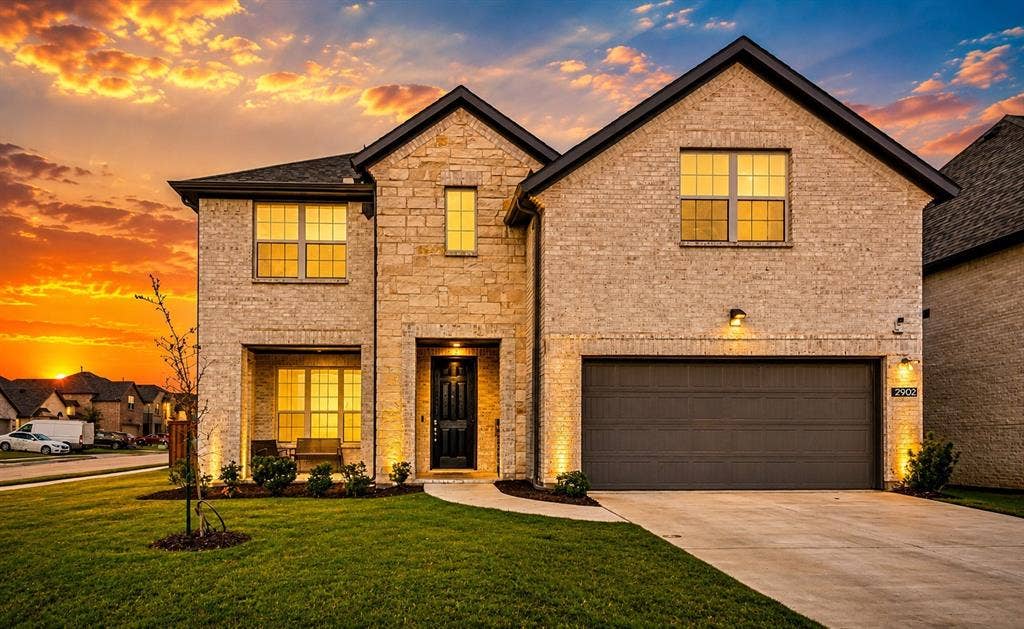 2902 Cremini Fls, Princeton, TX 75407 Two-story residence featuring a mixed brick and stone facade, an attached two-car garage, established front landscaping, and an inviting covered entry