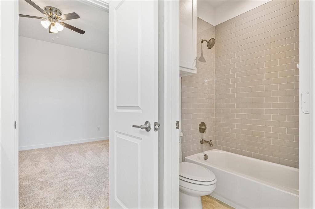 Bathroom with a subway tile shower surround, bathtub, and toilet