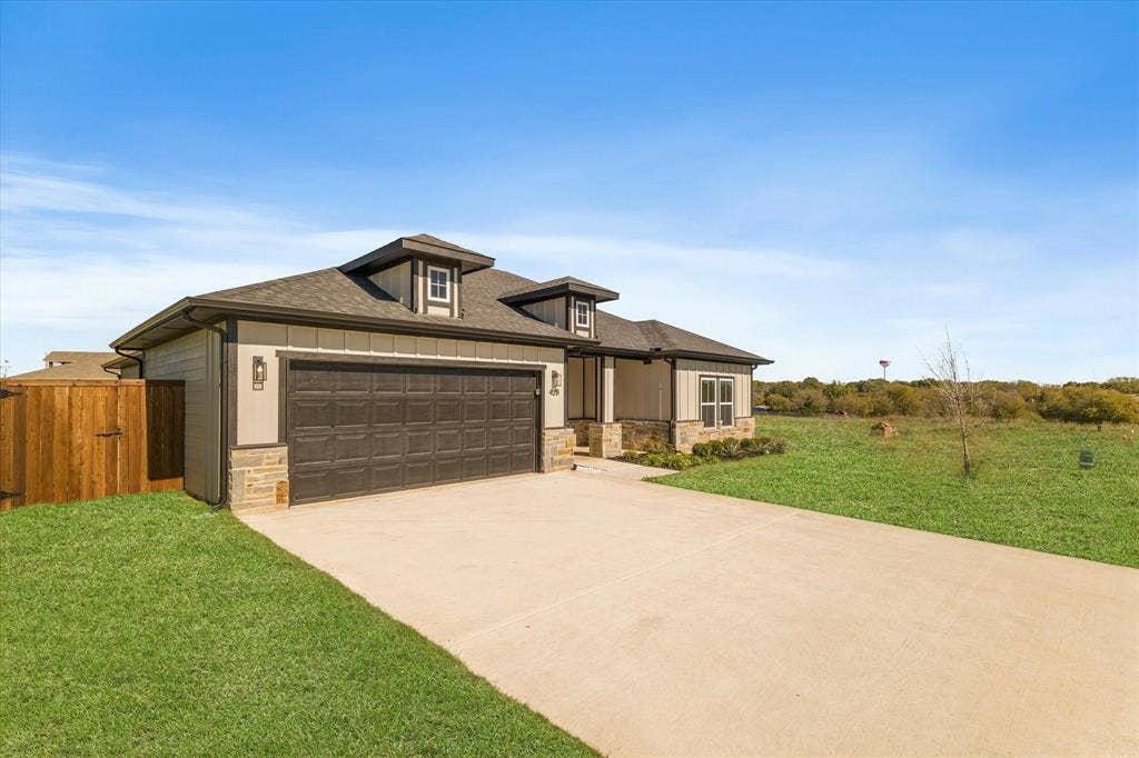 Exterior featuring stone accents, a two-car garage, dormer windows, and a concrete driveway