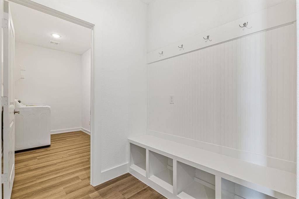 Built-in bench with storage cubbies, beadboard wall paneling, and wall-mounted coat hooks