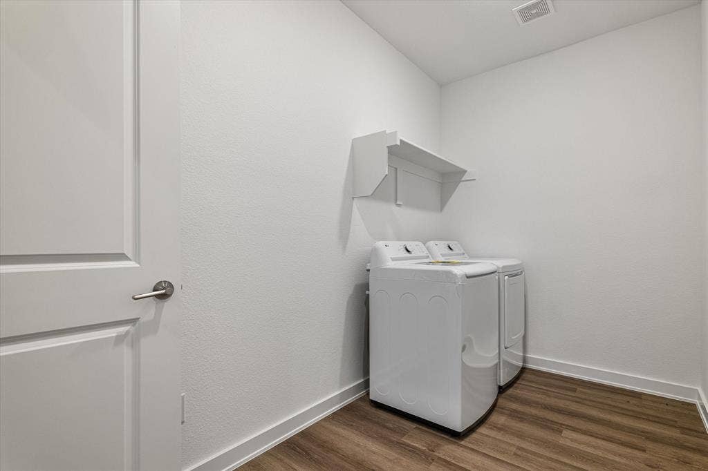 Laundry area featuring wood-finish flooring, white walls, and built-in shelving