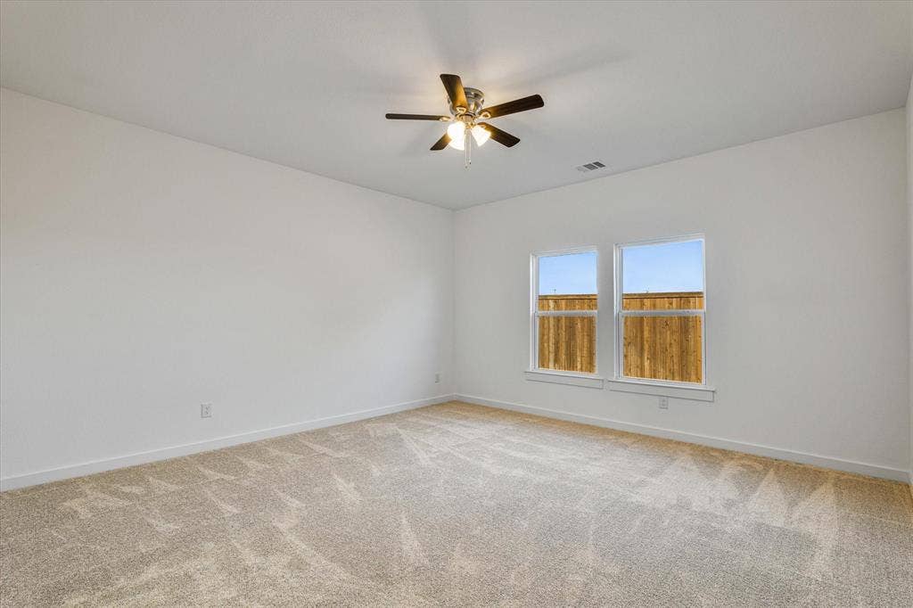 Two large windows, ceiling fan with integrated lighting, and neutral carpet flooring