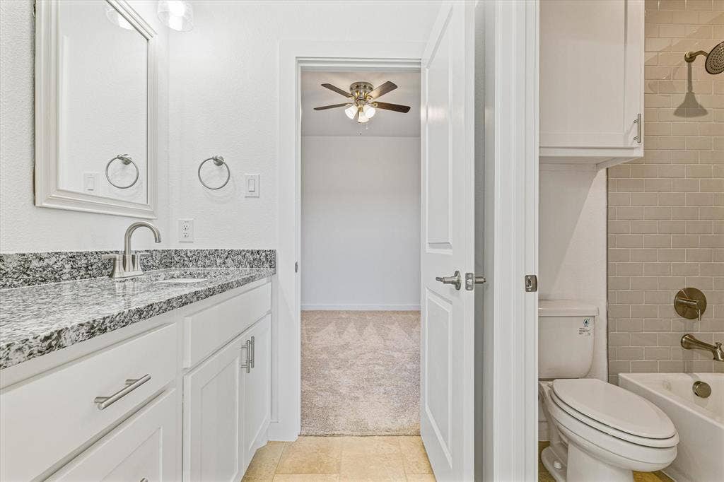 White vanity with a speckled countertop, a rectangular mirror, and brushed nickel fixtures